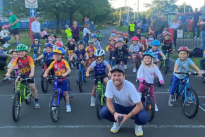 Mark Cavendish at the front with lots of kids on bikes behind him
